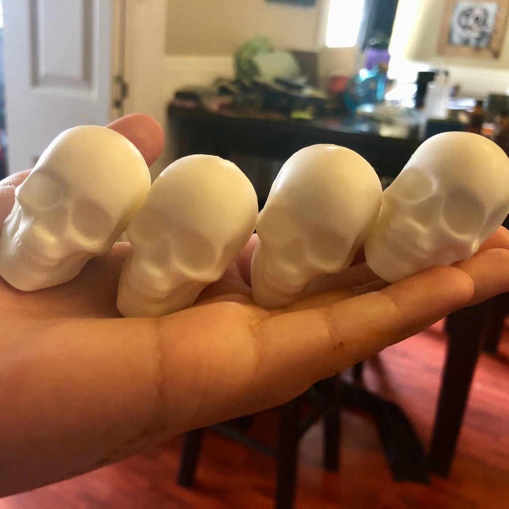 Four mini skull soaps held in a hand