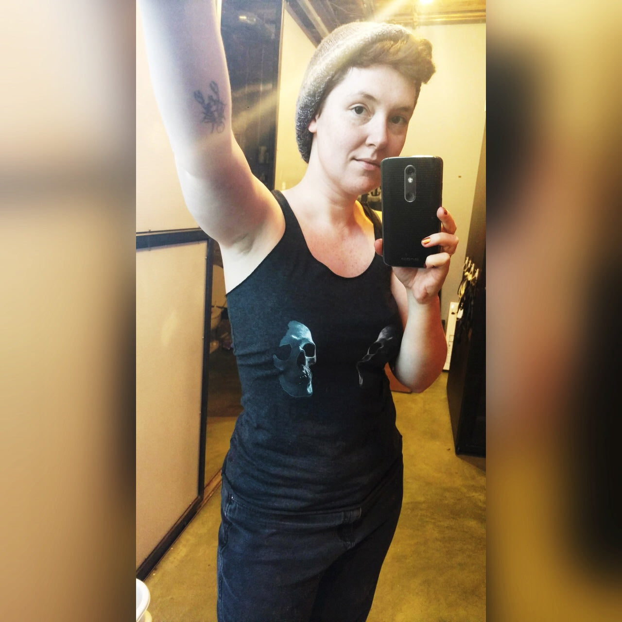 Person taking a selfie wearing racerback tank top with two skulls