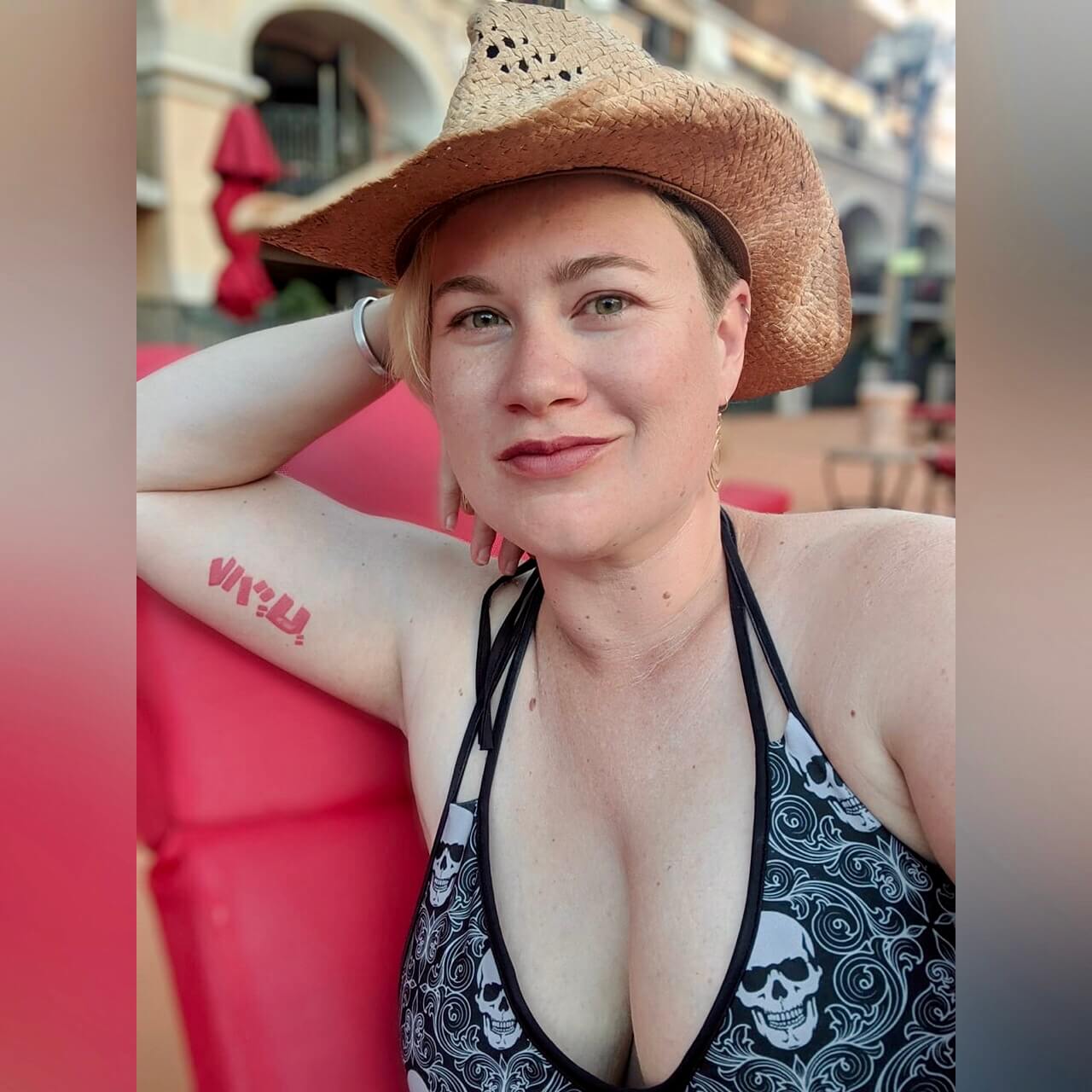 woman in cowboy hat and tattoo wearing skeleton wallpaper bikini top