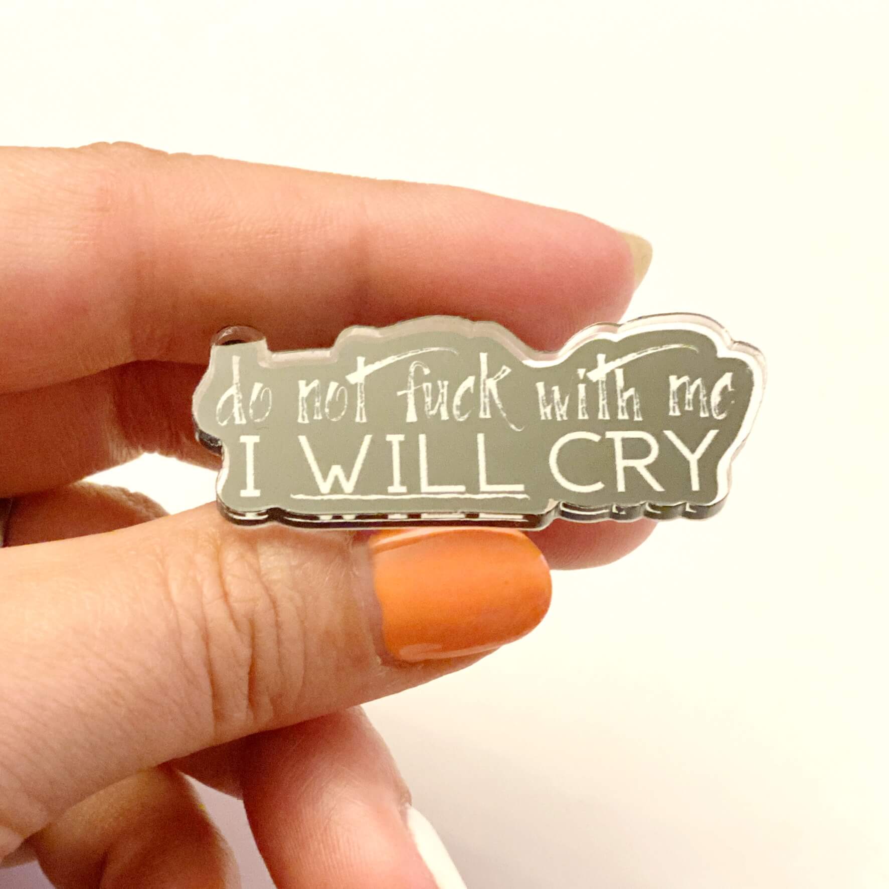 Close up of fingers holding an I will cry pin