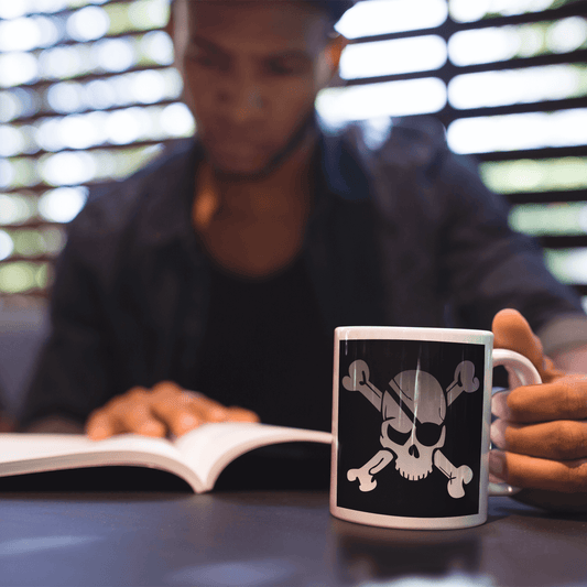 Man studying holding coffee mug with pirate skull and eye patch