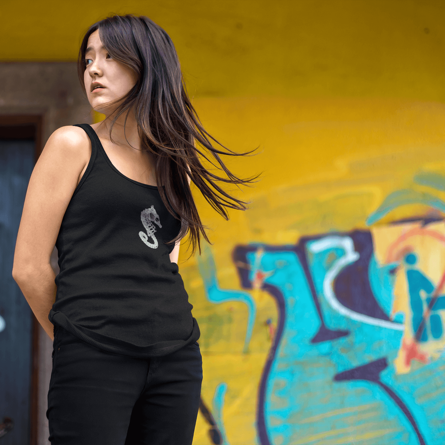 Woman with long hair in seahorse skeleton tank top in front of graffiti