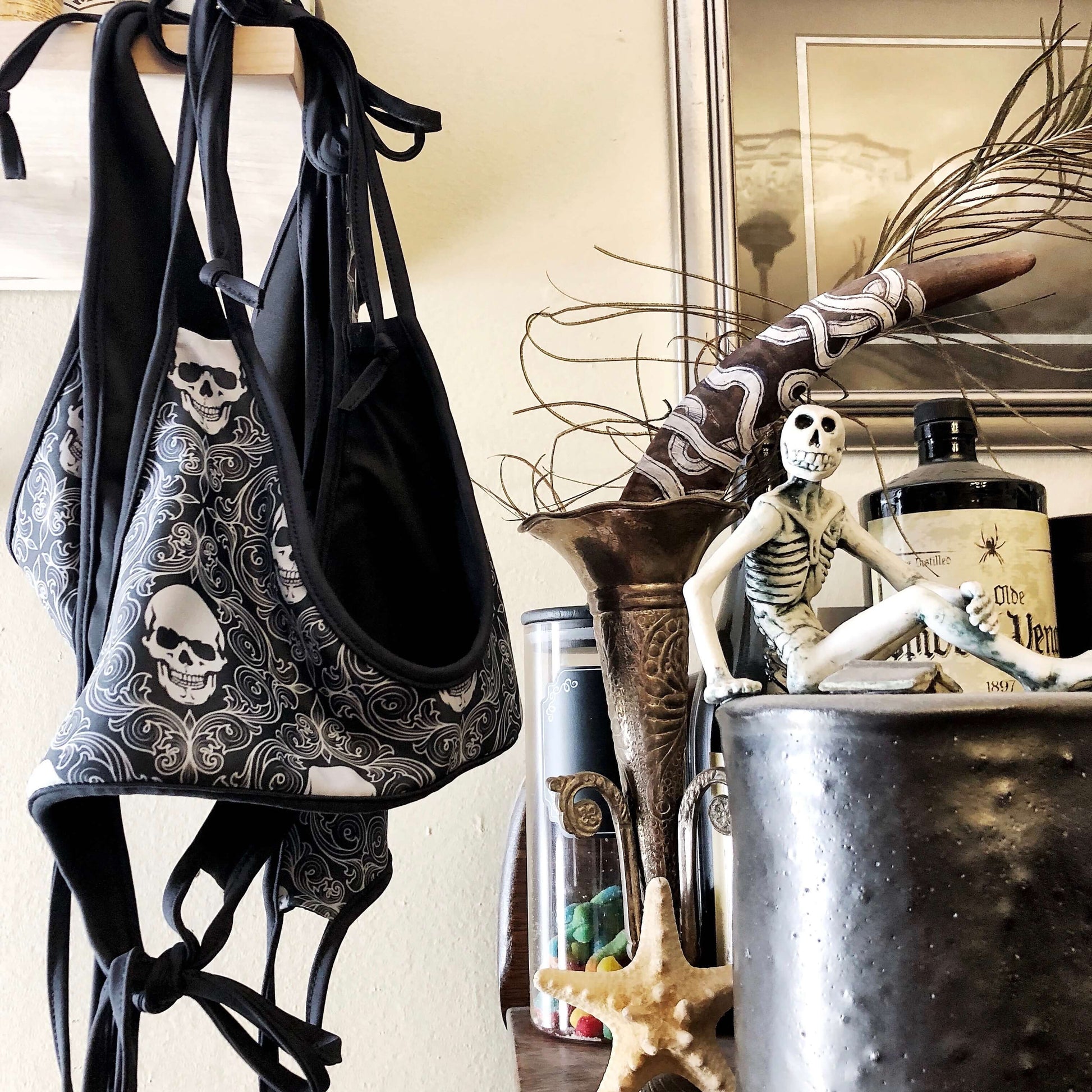 Reversible black and skull print bikini hanging next to skull and skeleton artwork