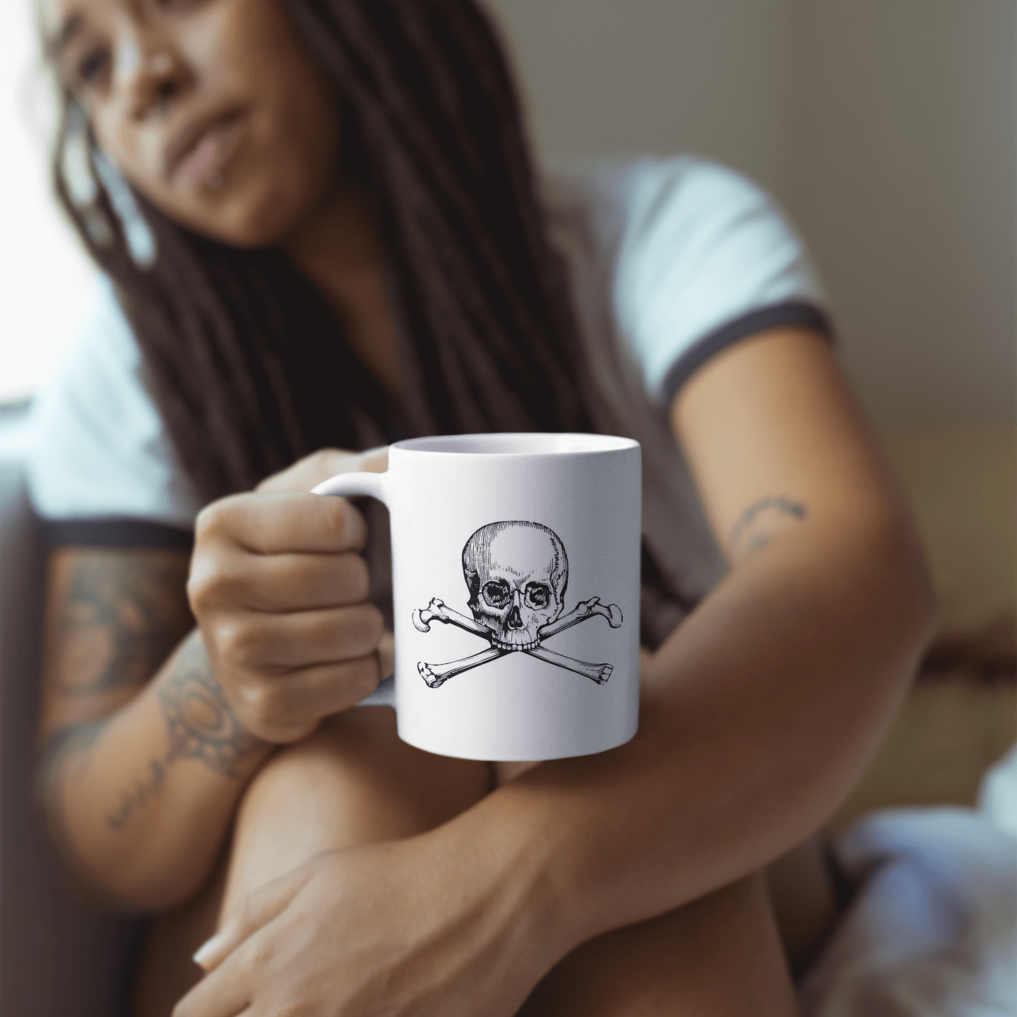 Woman holding white coffee mug with skull and crossbones