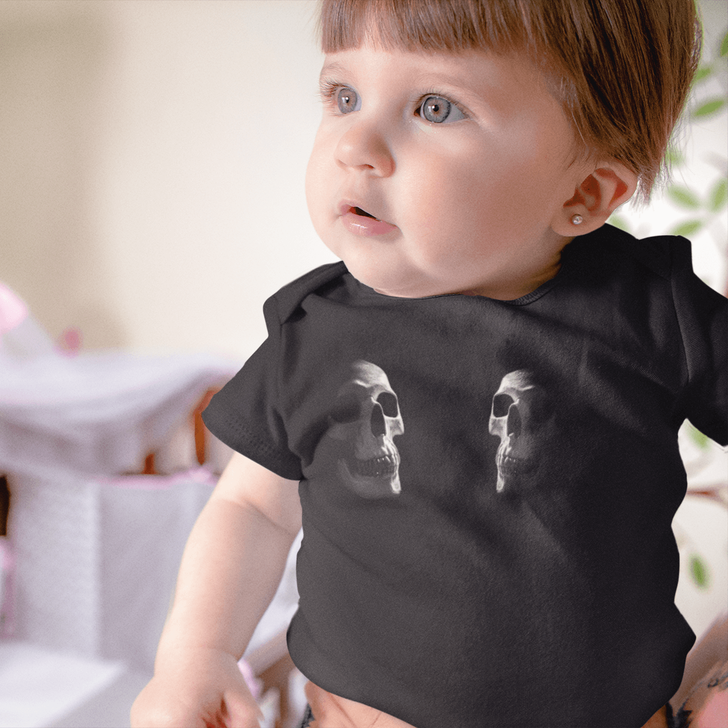 Baby wearing black onesie with two skulls facing each other
