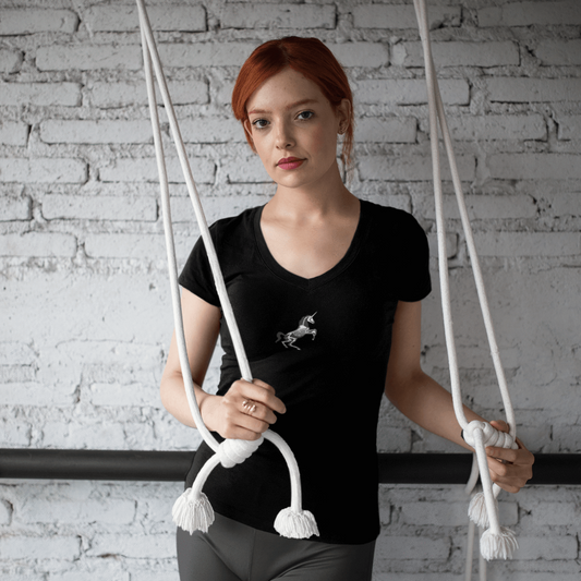 woman in unicorn skeleton deep v-neck t-shirt and grey leggings holds stretching cords at the gym